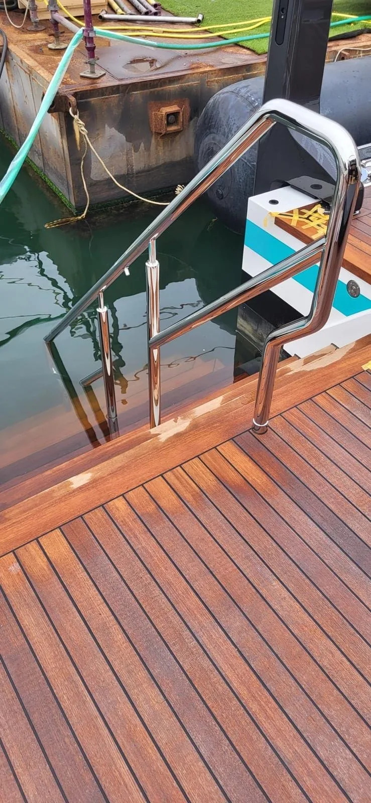 Polished stainless steel handrail detail next to teak deck