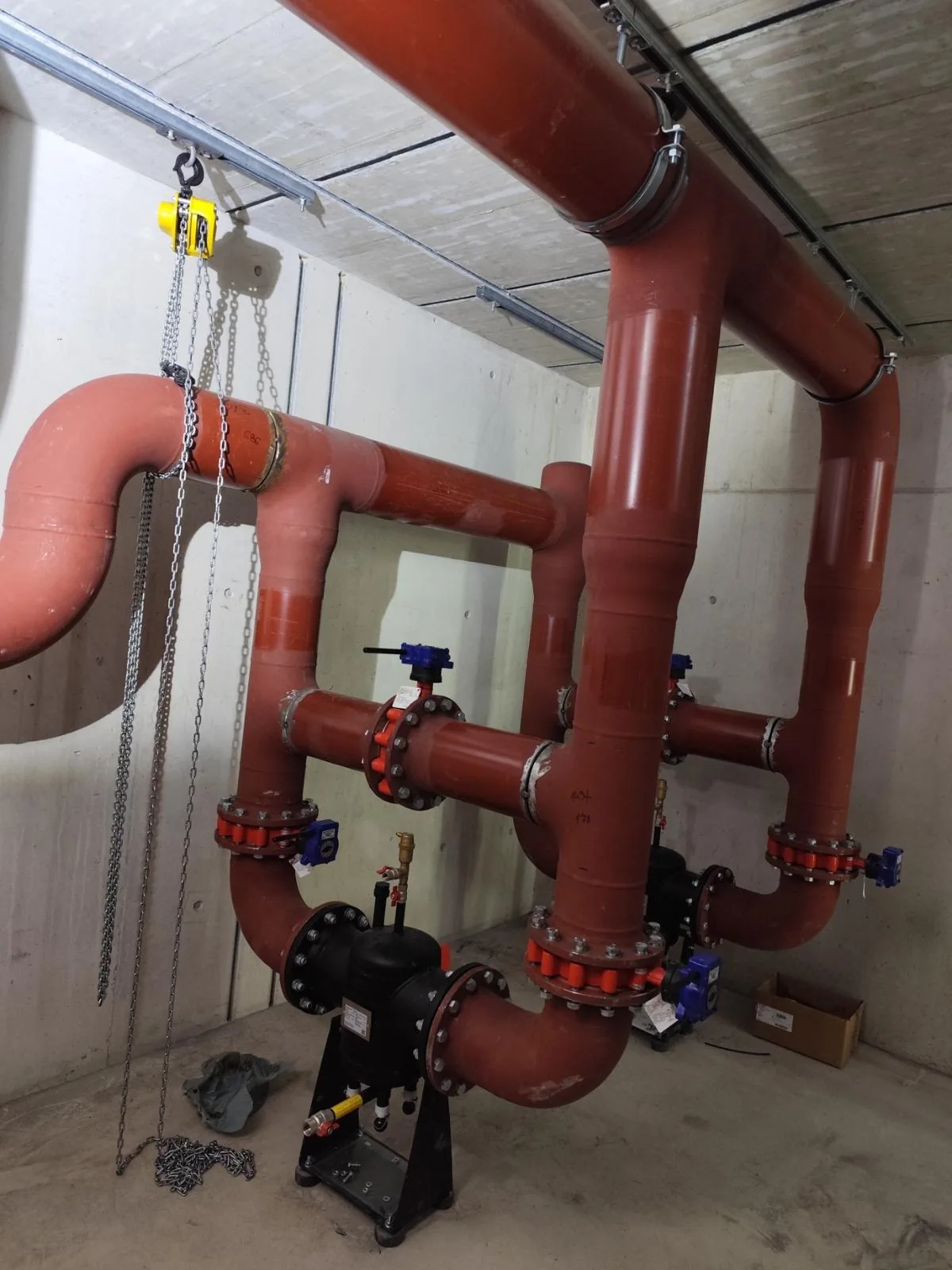 Vertical red pipework with valves in a technical area